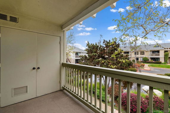 View from a balcony overlooking a landscaped area with trees and buildings.