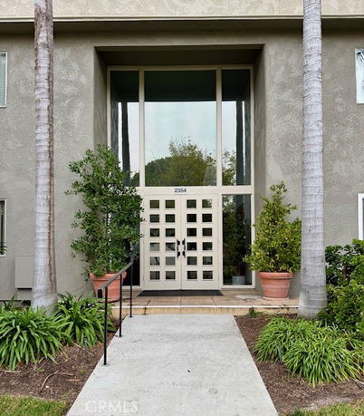 Front view of a building entrance with double glass doors and large windows.