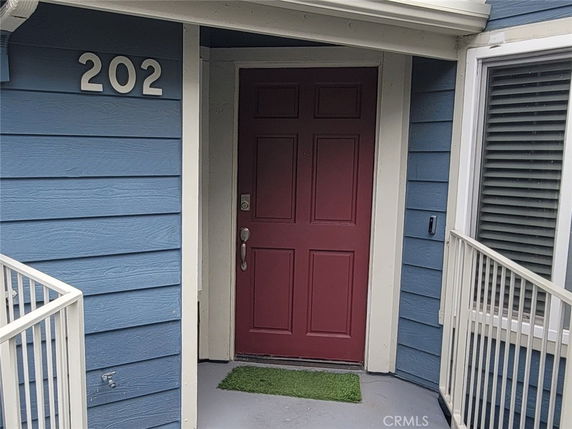 Entrance view of a blue house with a red door and white railings.