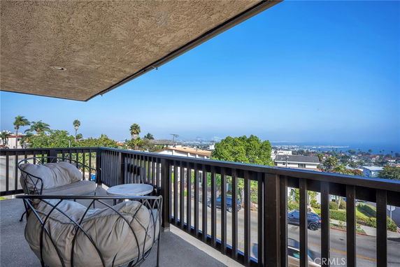 Panoramic view from a balcony overlooking a cityscape and ocean.