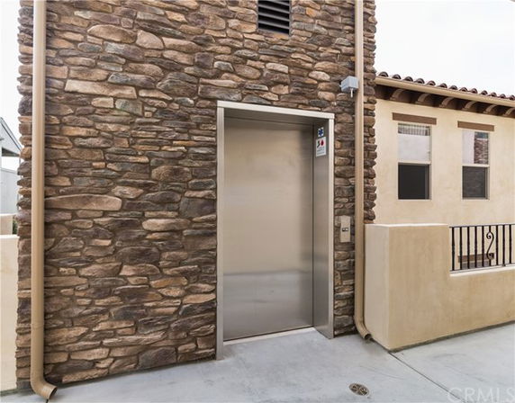 Front view of a building exterior with stone facade and an elevator entrance.