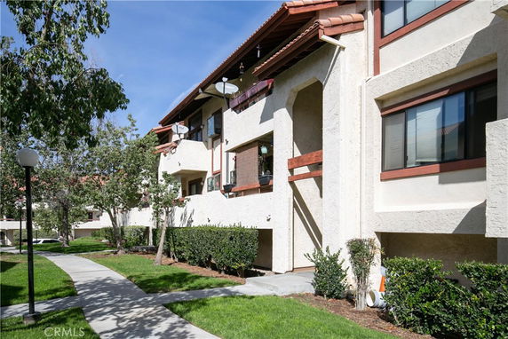 Front view of a multi-story residential building with a tiled roof and balconies.