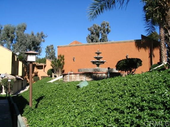 Front view of a building with a fountain and greenery in the foreground.