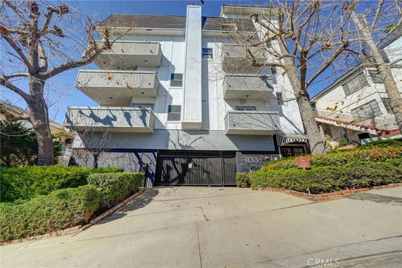 Front view of a multi-story building with balconies and a gated entrance.