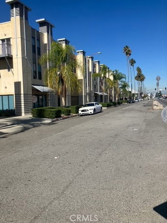 Front view of a multi-story building with a row of palm trees along the street.