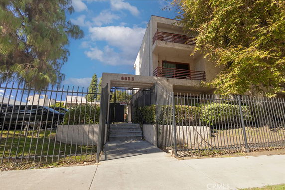 Front view of a multi-story building with balconies and a gated entrance.