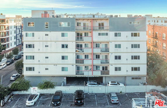 Front view of a multi-story residential building with balconies and parking area.