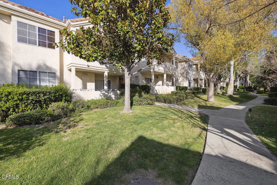 Front view of a multi-unit residential building with balconies and a garden.