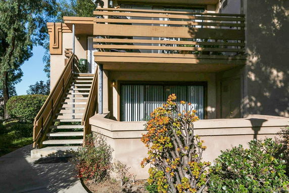 Front view of a two-story residential building with an exterior staircase and balcony.