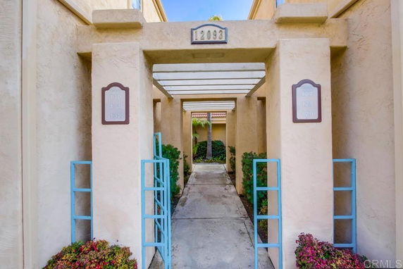 Front view of a residential entrance with stucco walls and overhanging beams.