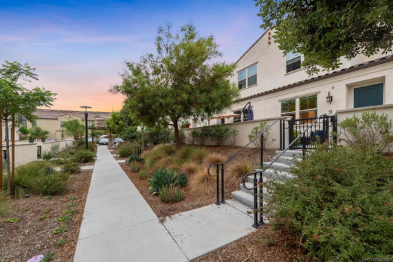 Front view of a two-story building with an outdoor staircase and landscaped pathway.