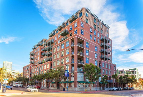 Front view of a multi-story brick apartment building with balconies.