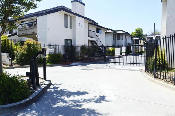 Front view of a gated residential building with two stories and multiple units.