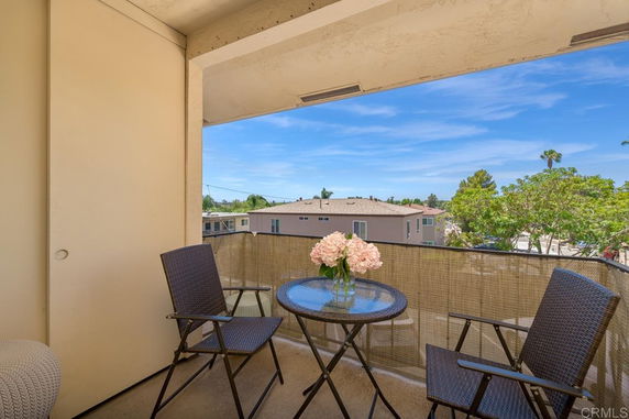 Balcony view overlooking nearby buildings and greenery.