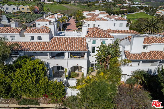 Front view of a multi-story house with white walls and red-tiled roof.
