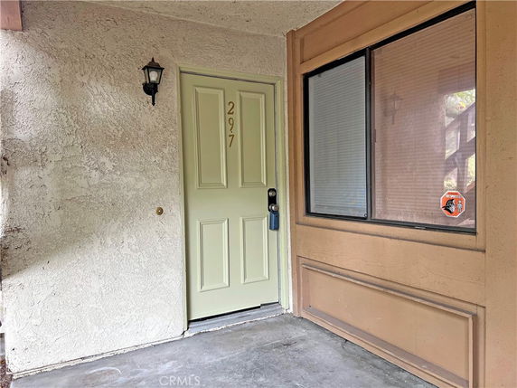 Front view of a building entrance with a light green door and a window beside it.