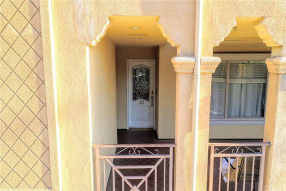 Front view of a building entrance with an ornate door and balcony railings.