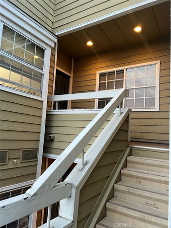 Staircase leading to the entrance of a multi-story building under a covered porch.
