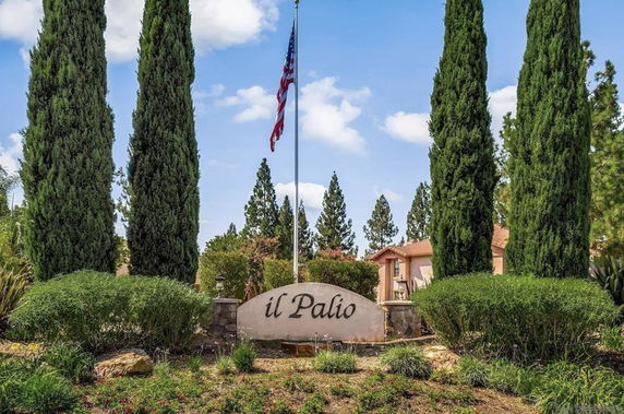 Front view of residential entrance with large sign and trees.
