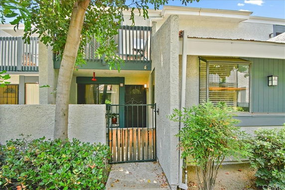 Front view of a two-story residential building with a small gated entrance and balcony.