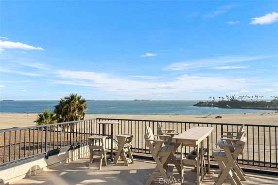 Panoramic view from a rooftop overlooking the beach and ocean, with outdoor seating.