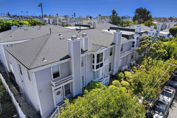 Elevated view of a multi-story house with multiple chimneys and white exterior.