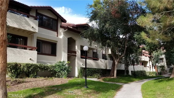 Front view of a multi-story residential building with arched roofs and balconies.