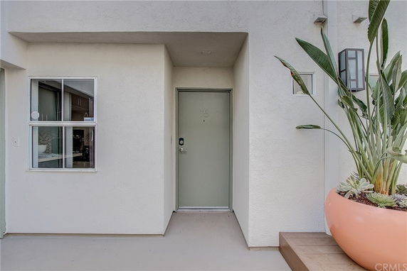 Front entrance of a house with a light-colored door and a window beside it.