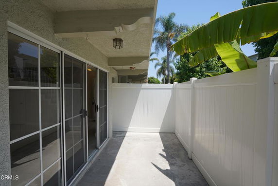 Outdoor area with sliding glass doors and white fence.