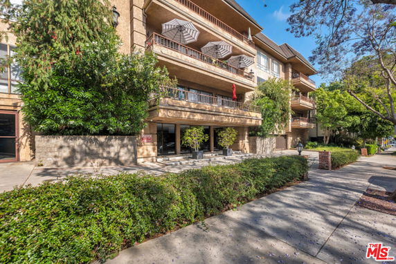 Front view of a multi-story building with balconies and outdoor seating.