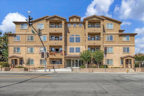 Front view of a multi-story apartment building with balconies and large windows.
