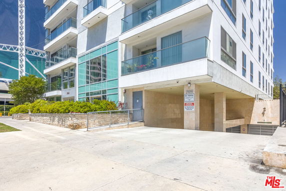 Front view of a multi-story building with balconies and a driveway.