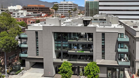 Front view of a modern multi-story building with large glass windows and balconies.