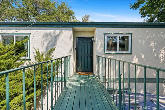 Front view of a house with a wooden walkway and green trim.
