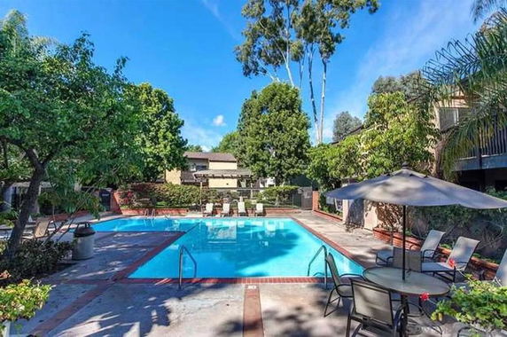Outdoor swimming pool with surrounding trees and patio furniture.