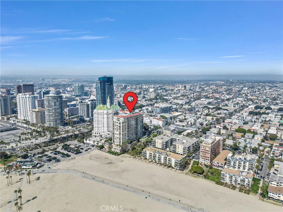 Panoramic view of a cityscape with high-rise buildings and a sandy beach in the foreground.