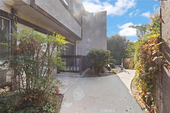 Front view of a two-story building with a walkway surrounded by vegetation.