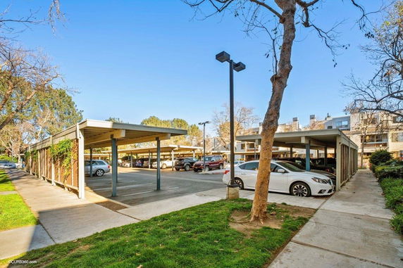 Outdoor parking area with covered parking spaces and several parked cars.