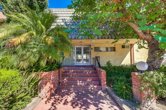 Front view of a house with a brick-paved walkway and foliage.