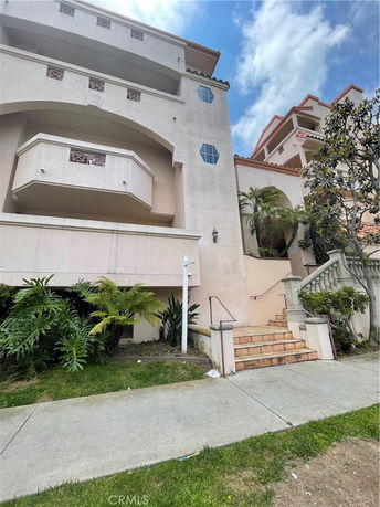 Front view of a multi-story building with balconies and staircase entrance.