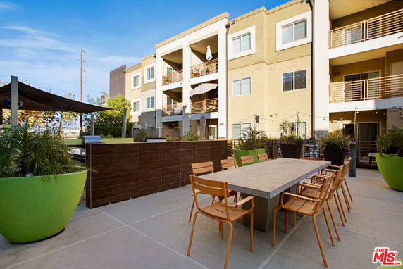 Front view of a multi-story residential building with balconies and outdoor seating area.