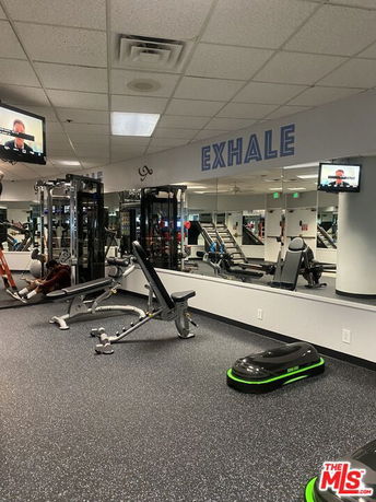 Gym area with exercise machines and mirrors on the wall.