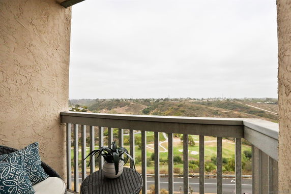 Balcony view overlooking a hilly landscape and green areas.