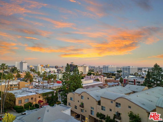 Panoramic view of a cityscape with multiple buildings and a colorful sky.