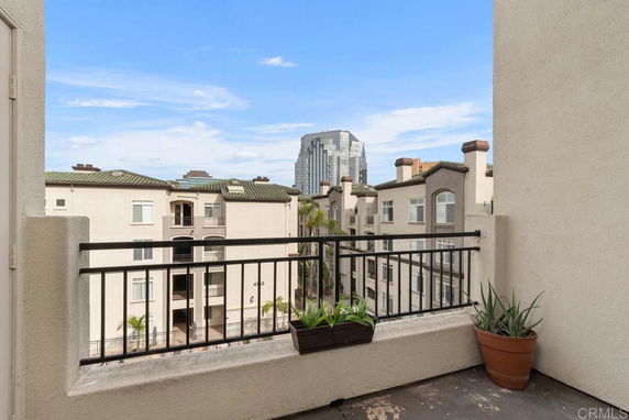 View from a balcony overlooking nearby buildings and a distant skyscraper.