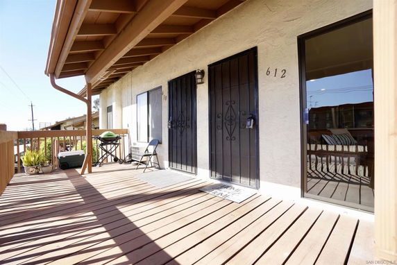 Front view of a building with a wooden deck and metal door.