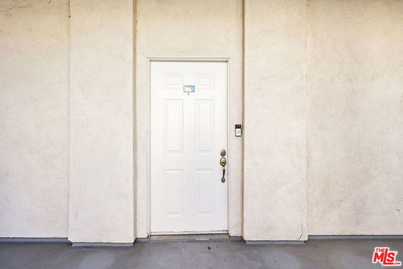 Front view of a building entrance with a white door and handle.