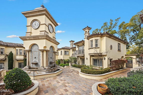 Front view of a residential building complex with clock tower and decorative fountains.