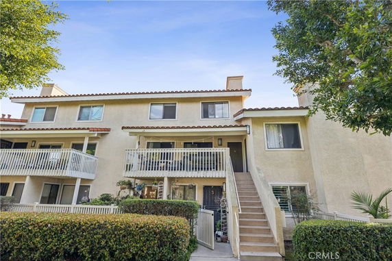 Front view of a multi-story house with balconies and an exterior staircase.