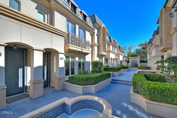 Front view of townhouses with arched doorways and landscaped pathways.